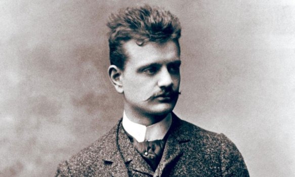 The composer Jean Sibelius as a young man, in a suit, vest, and high color, sporting a mustasche