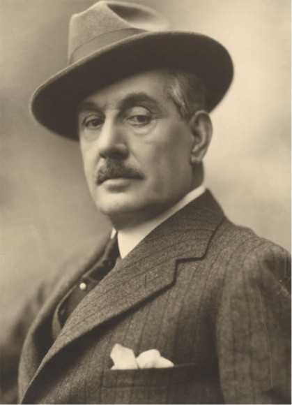 A vintage black and white portrait of a man wearing a suit and a fedora, looking confidently at the camera.